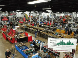 Wide angle view of a bustling gun show with various booths and displays