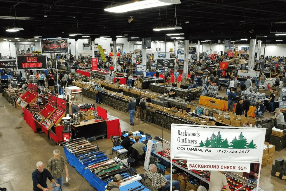 Wide angle view of a bustling gun show with various booths and displays