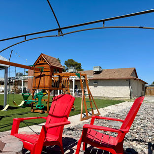 Red chairs and kids playground with swings at Rancho Brazil backyard in Las Vegas
