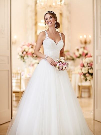 Bride in white dress holding bouquet in a The Wedding Shop.