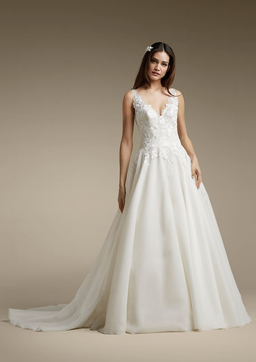 Young woman in elegant white wedding dress posing with a train.