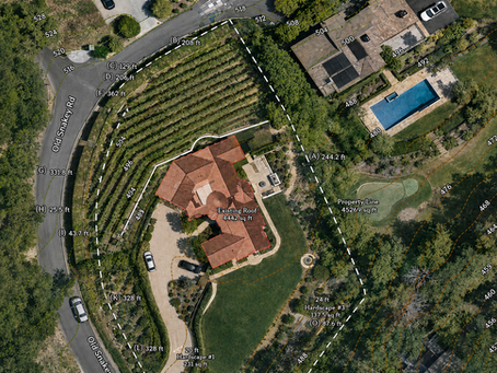 Simple overhead diagram of a residential property and home footprint, rendered in soft white with a light gray roofline visible through a subtle aerial base. A gentle teal-tinted overlay highlights the zoning setback area around the home, with small rounded checkmark icons at each property line suggesting "checked and compliant." Trees and driveway sketched lightly in the background. Parcel boundary in dark navy, not harsh. Feels like a friendly, reassuring homeowner explainer graphic — not a stamped technical drawing. No people, no vehicles, no dense text. 16:9.