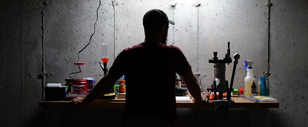 A man in shadow stands at his reloading bench, pondering the nature of dispersion