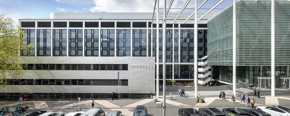Modern building with glass facade, labeled "IMPERIAL". People walking on the sidewalk. Bicycles and cars parked in front; sunny day.