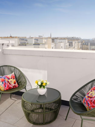 Rooftop terrace with chairs, table, city view