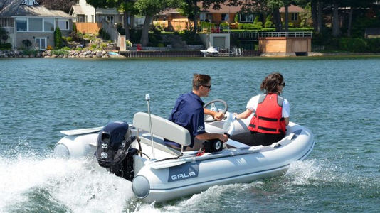 Man driving inflatable boat with passenger on lake