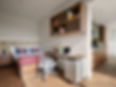 Modern studio apartment with bed, desk, and kitchenette