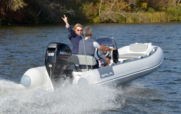 Two people in an ATLANTIS boat, one waving during a ride.
