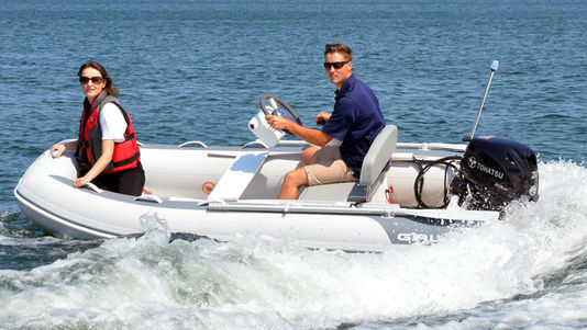Man driving white inflatable boat with woman on sunny water