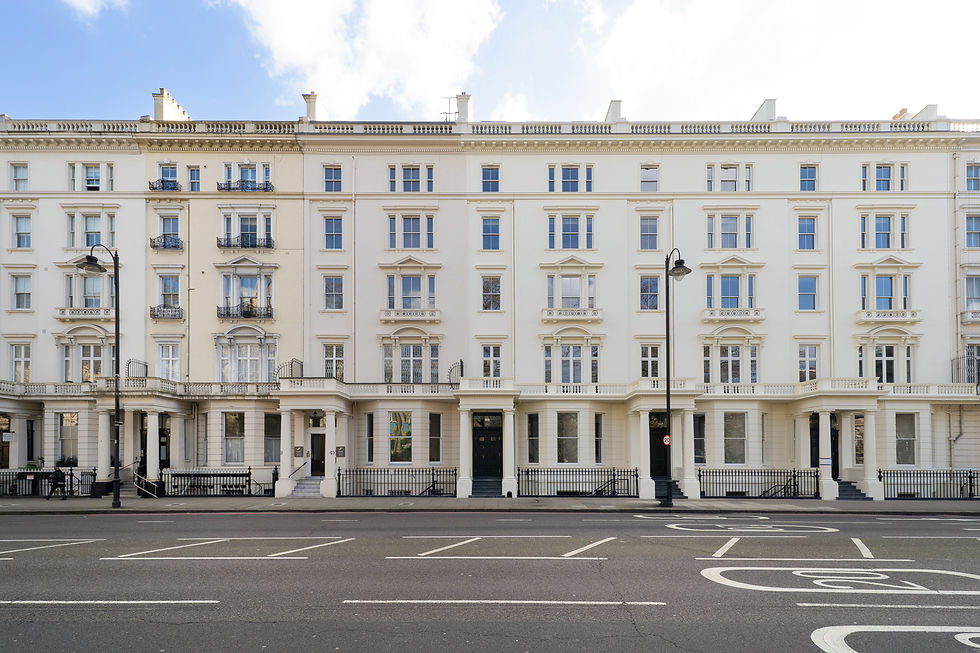 Elegant white residential building with large windows and balconies, flanked by street lamps. Clear blue sky and empty road in foreground.