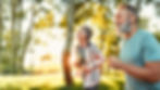 Senior couple jogging in a sunny park.