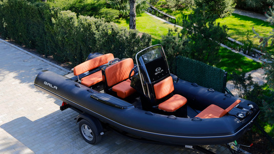 Black inflatable boat with orange seats on trailer