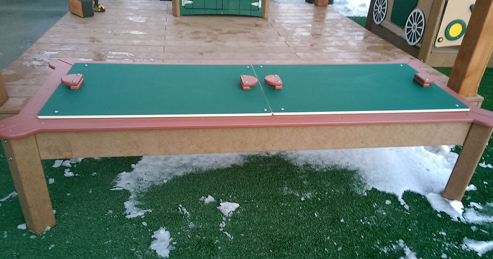 Thumbnail: Green and brown water table with inset basin, drain, and water spill post with hose hookup on woodchips at daycare school