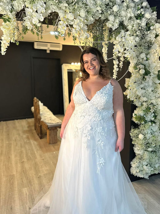 Plus size A line lace wedding dress with floral appliqué bodice and plunge neckline available at Wedding Belles Love bridal boutique in Stoke on Trent
