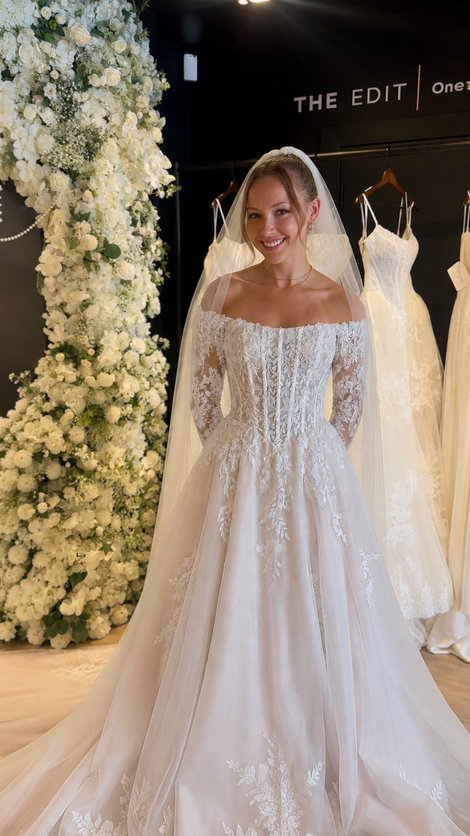 Bride wearing an ivory lace A-line wedding dress with a dramatic floral lace train at Wedding Belles Love bridal boutique.