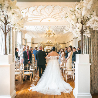 Bride admiring her Atlantis wedding dress with lace detailing and tulle sleeves.