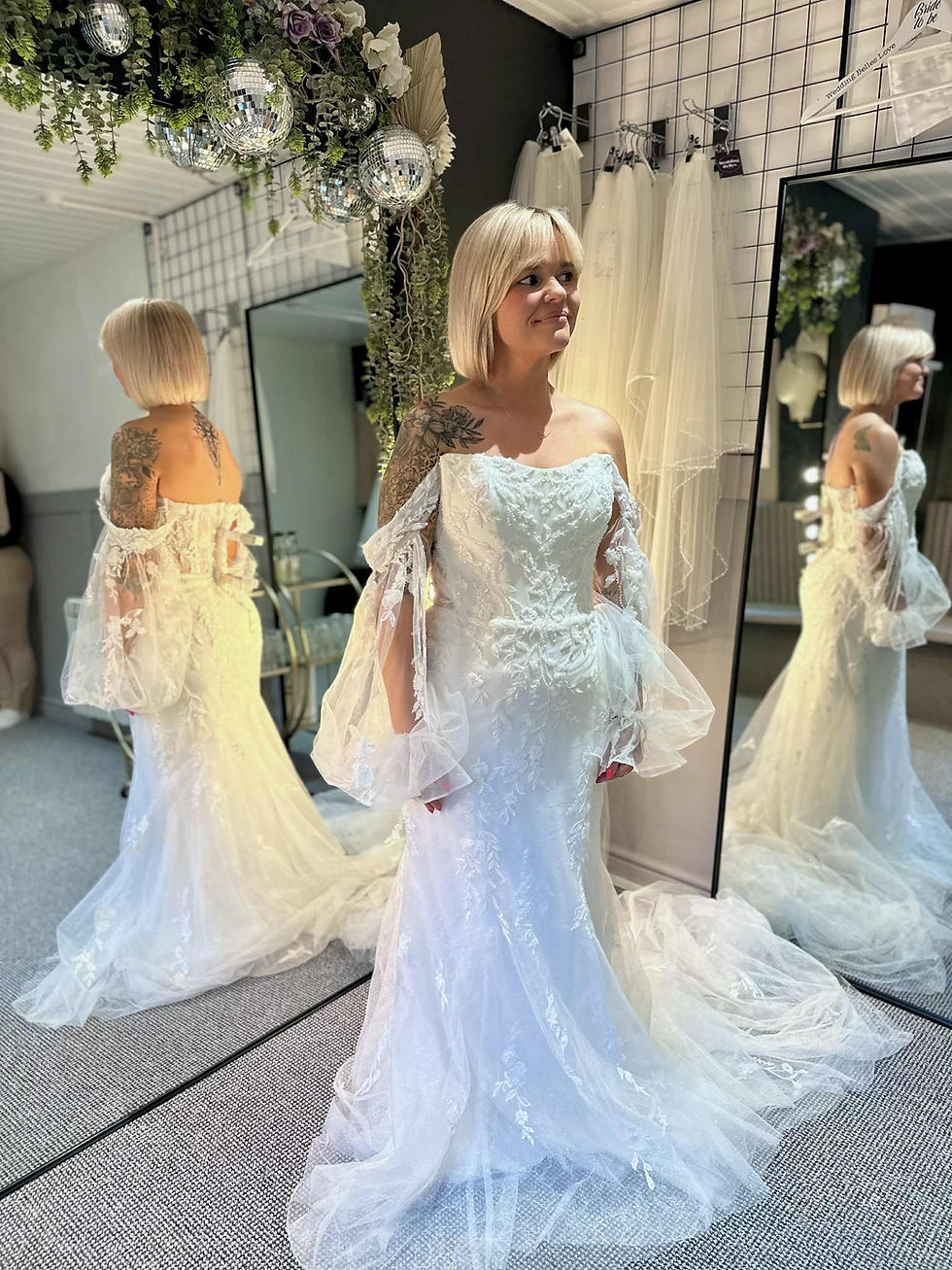 Excited bride in bridal shop holding the skirt of her gown with joy