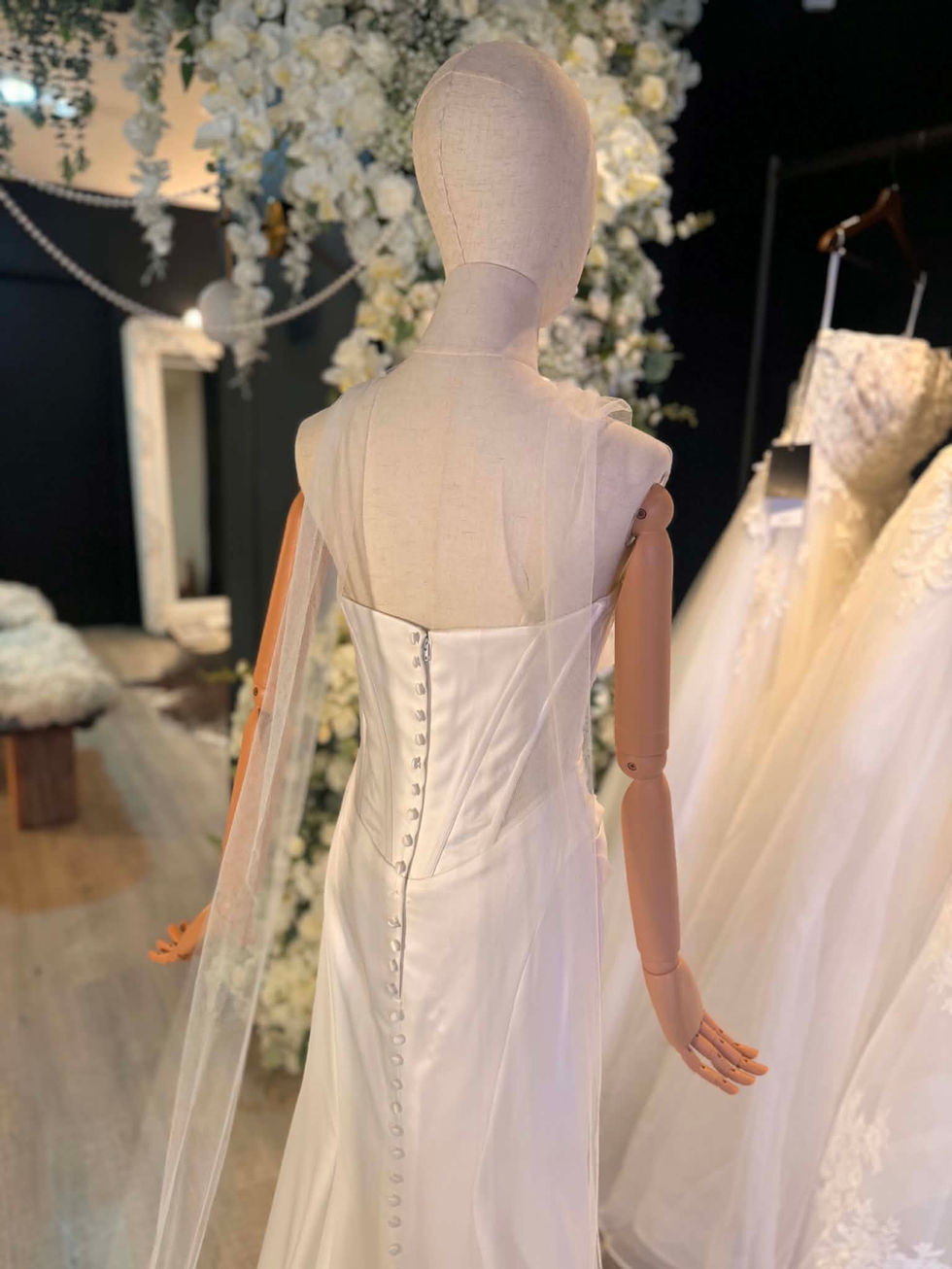 Madi Lane ivory sheer tulle bridal scarf with delicate floral embroidery at both ends, draped over the shoulders of a wedding