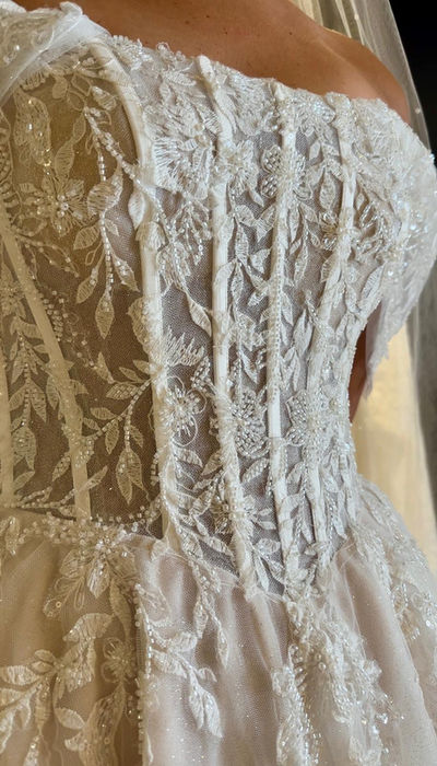 Etta by Mavery Hugh champagne A Line wedding dress size 14 at Wedding Belles Love Stone Staffordshire with off the shoulder neckline, structured corset bodice, botanical lace, sparkle tulle and sweeping train.