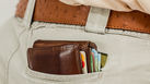 A brown filled wallet sticking out the back of light grey chinos