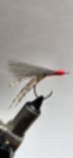 Hand tied flies for surf fishing for pompano in a vise.