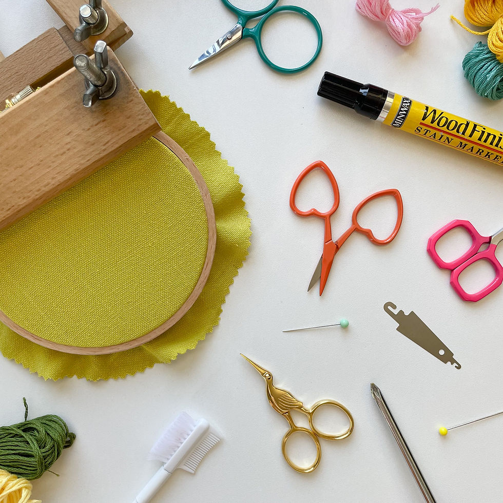 Photo of embroidery supplies scattered on a white surface.