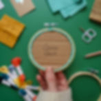 Embroidery project featuring a colorful sunset over water and birds in the background, held with back facing forward.