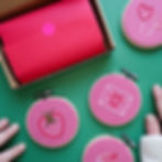 Three projects featuring a love note, strawberry, cupcake, and heart shaped lollipops next to an embroidery kit box