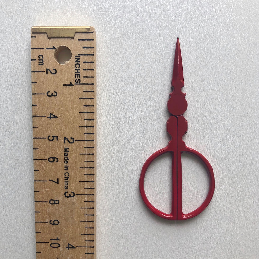 Thumbnail: A long pair of red embroidery scissors with a circular design on the handles next to a ruler on a white surface.