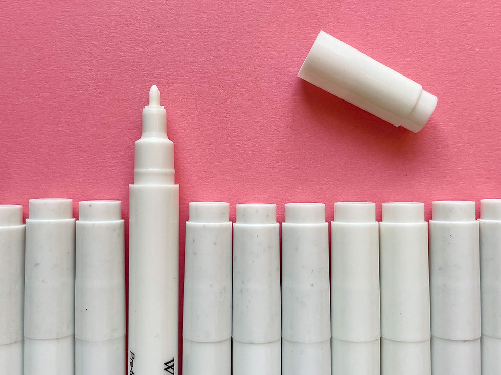 Photo of a row of white pens lined up on top of a pink surface. One pen has its cap removed, revealing a small white nib.
