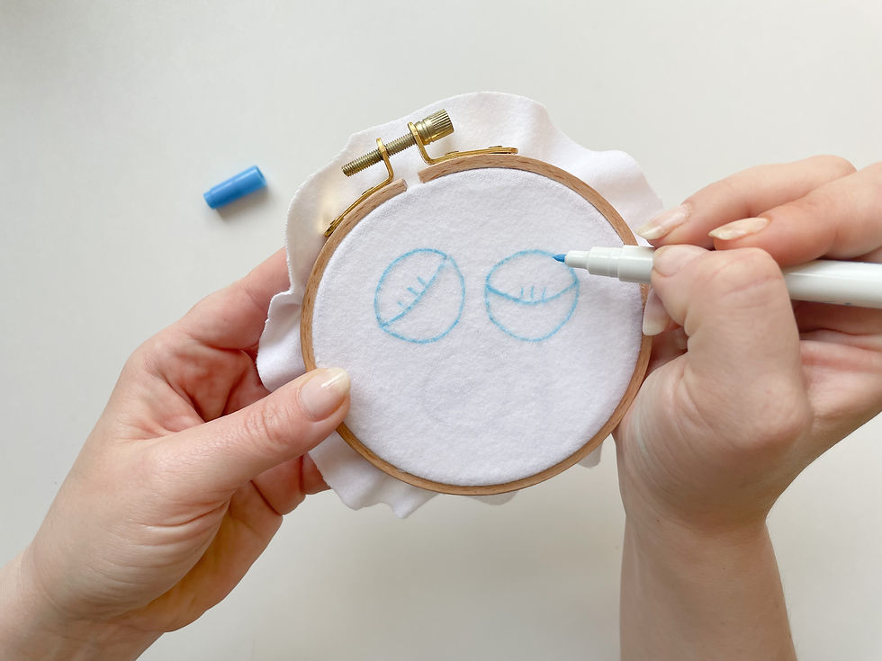 Photo of Hope drawing tulips onto a white fabric using a blue pen.