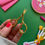 Thumbnail: Golden rose embroidery scissors held above a surface upon which are various embroidery supplies from a kit