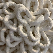 White rope-like fiber art in the shape of a flower on a white wall