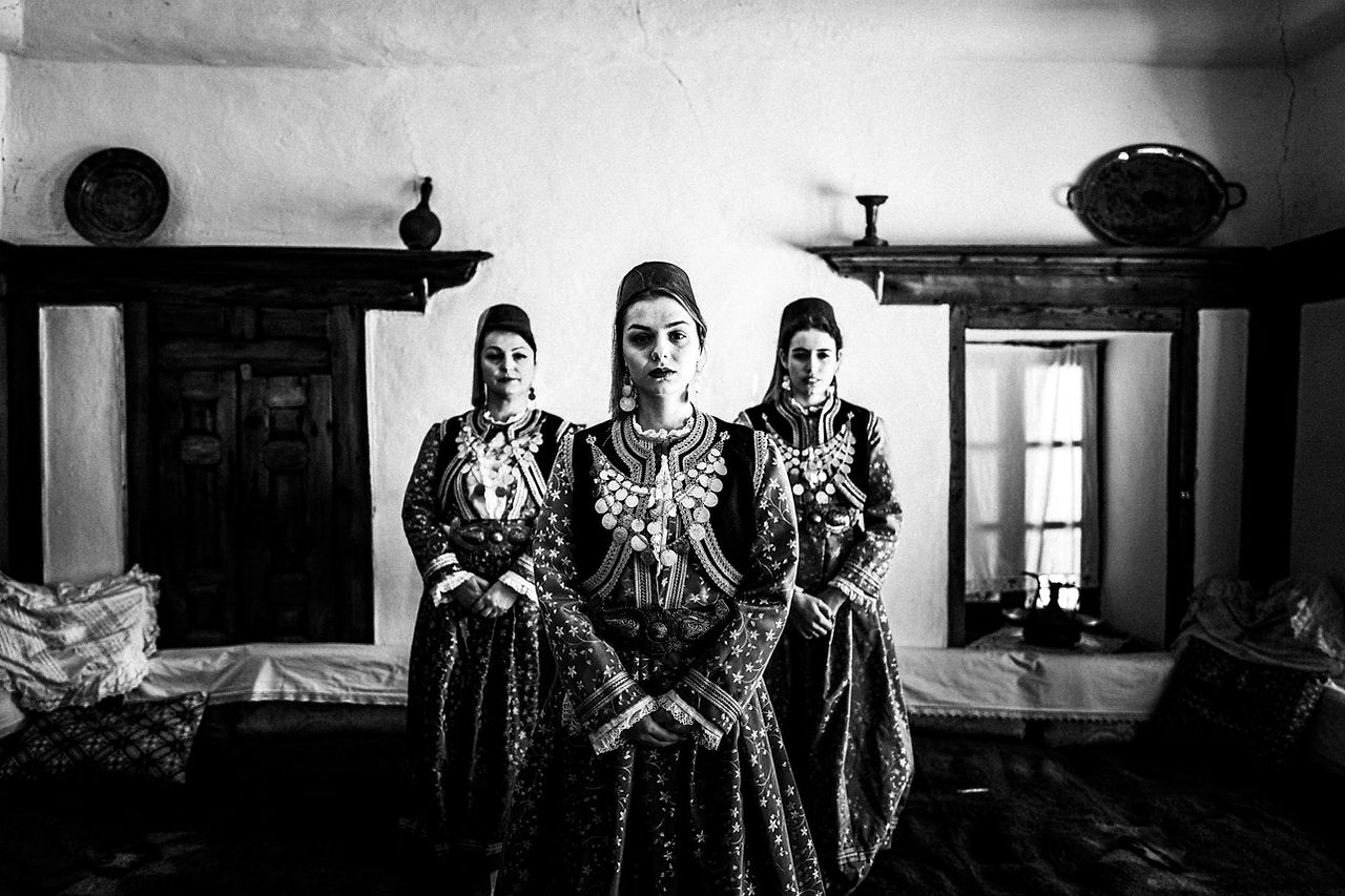 Three women inside the 'ontas' of a local traditional Mansion. Kastoria, Macedonia, Greece. Black and white photograph by George Tatakis