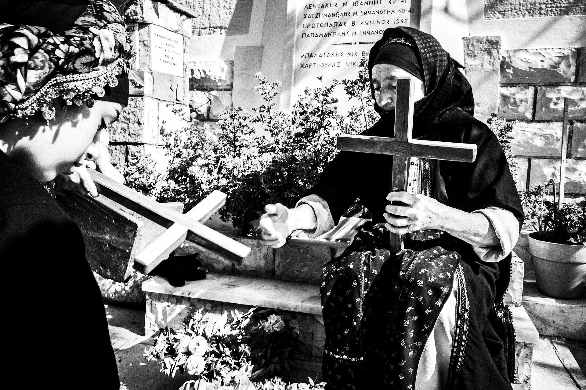 A girl with her grandmother, decorating wooden crosses for the Epitaphios. Olympos, Karpathos, Greece