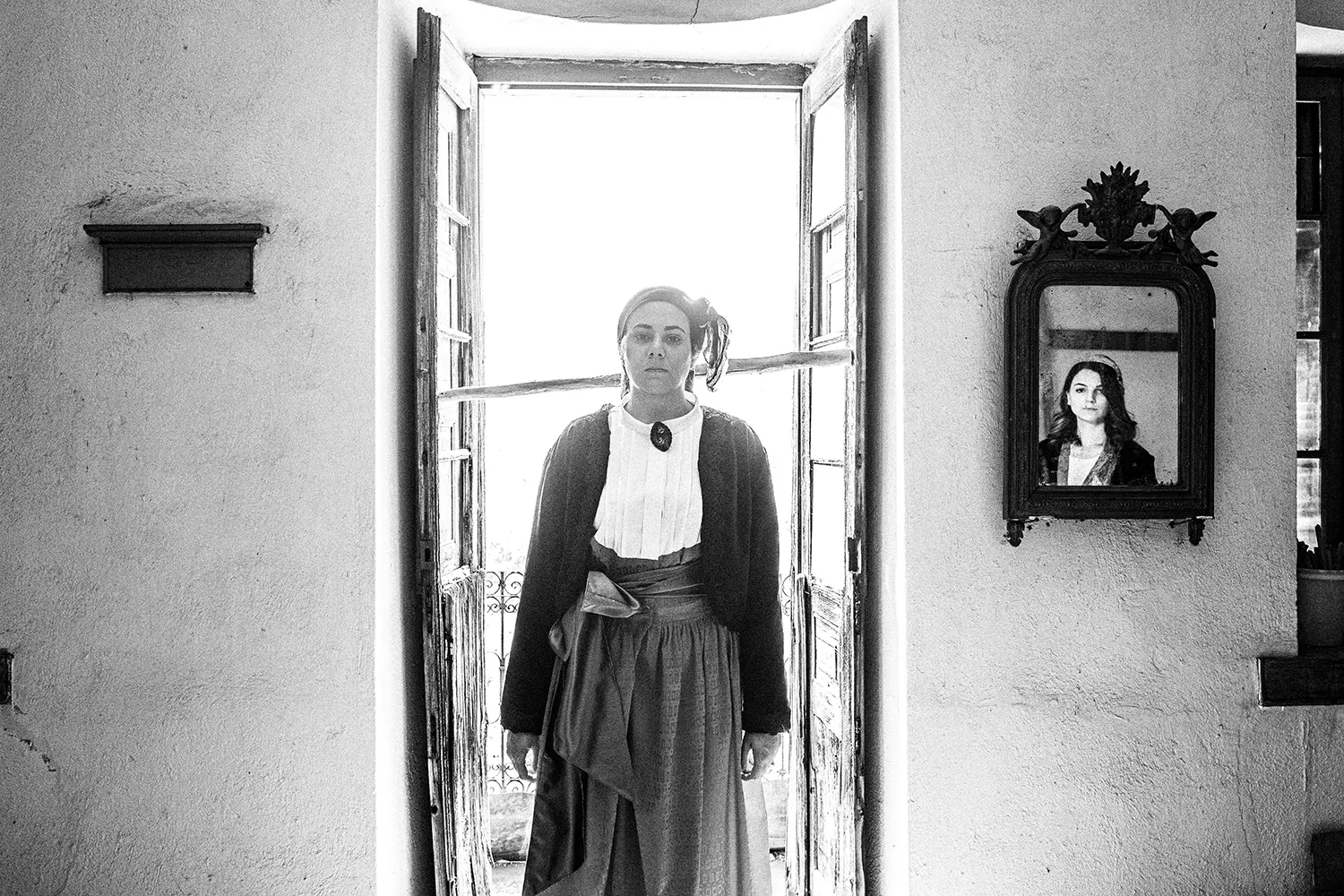 A woman in front of a balcony in Pinakates, in the local attire of Pelion, Thessaly, Greece. Black and white photography by George Tatakis