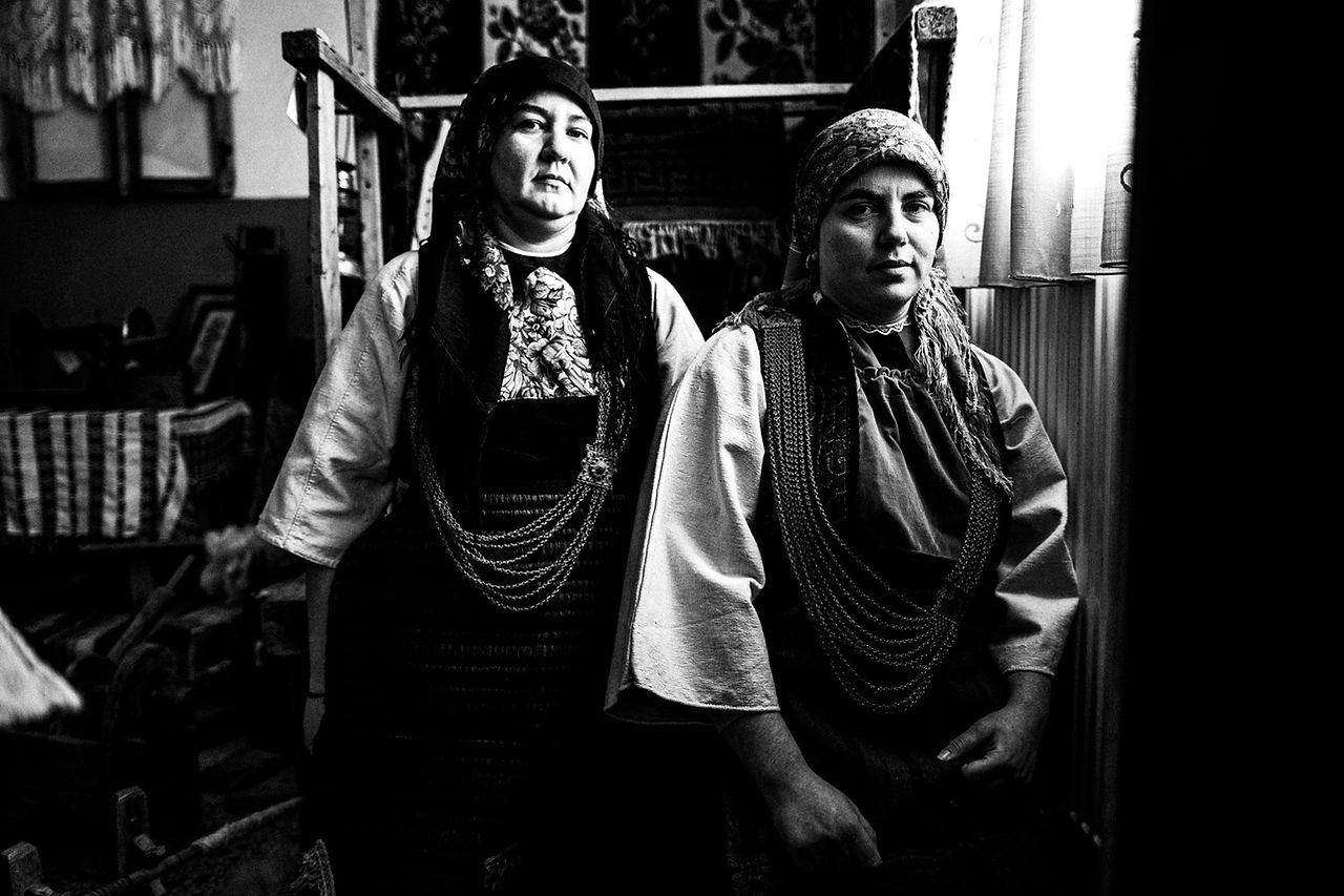 Two women in their local folklore dresses. Skopos, Florina, Macedonia, Greece. Black and white photograph by George Tatakis