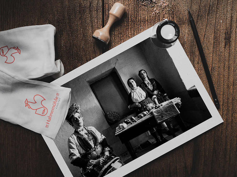 Women in the local dresses of the villages of the valley of Naoussa, Imathia, Greece. A fine-art black-and-white photographic print on a wooden table, by George Tatakis.