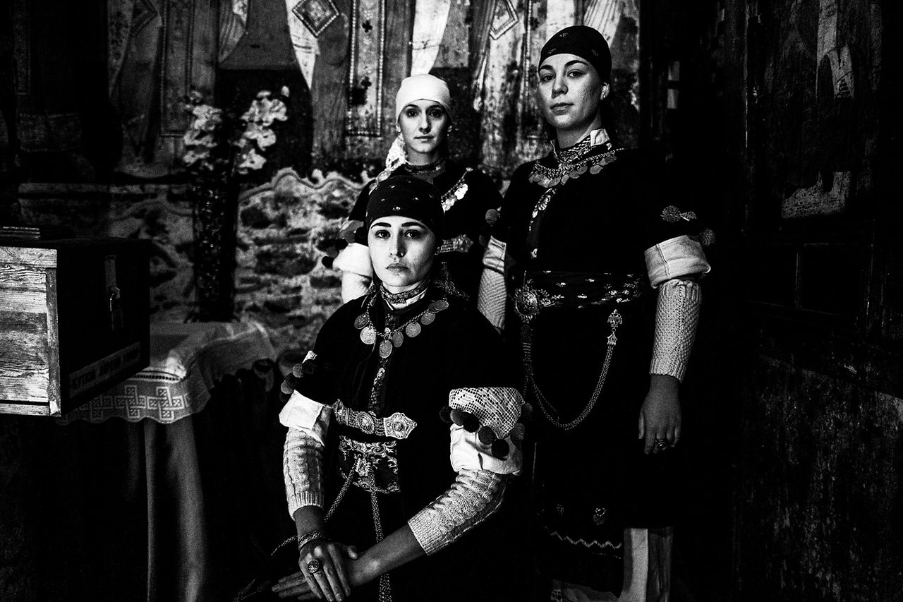 Three women posing inside a church at Prespes, Macedonia, Greece. Black and white photograph by George Tatakis