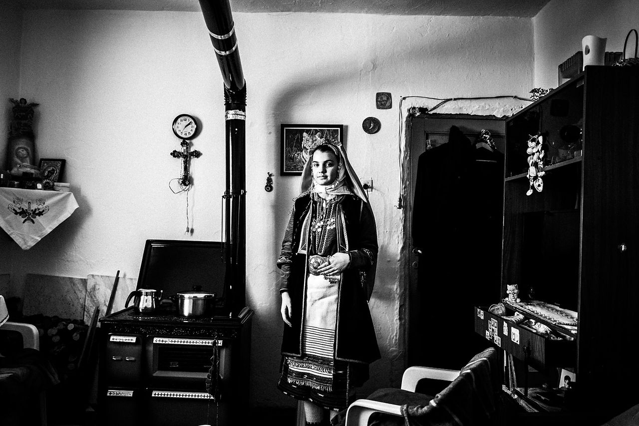 A bride in the traditional dress inside a local home. Volax, Drama, Macedonia, Greece. Black and white photograph by George Tatakis