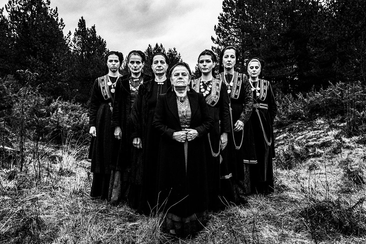 A group of women in an arrow formation, wearing the local Vlach folklore dresses. Seli mountain, Imathia, Macedonia, Greece. Black and white photograph by George Tatakis