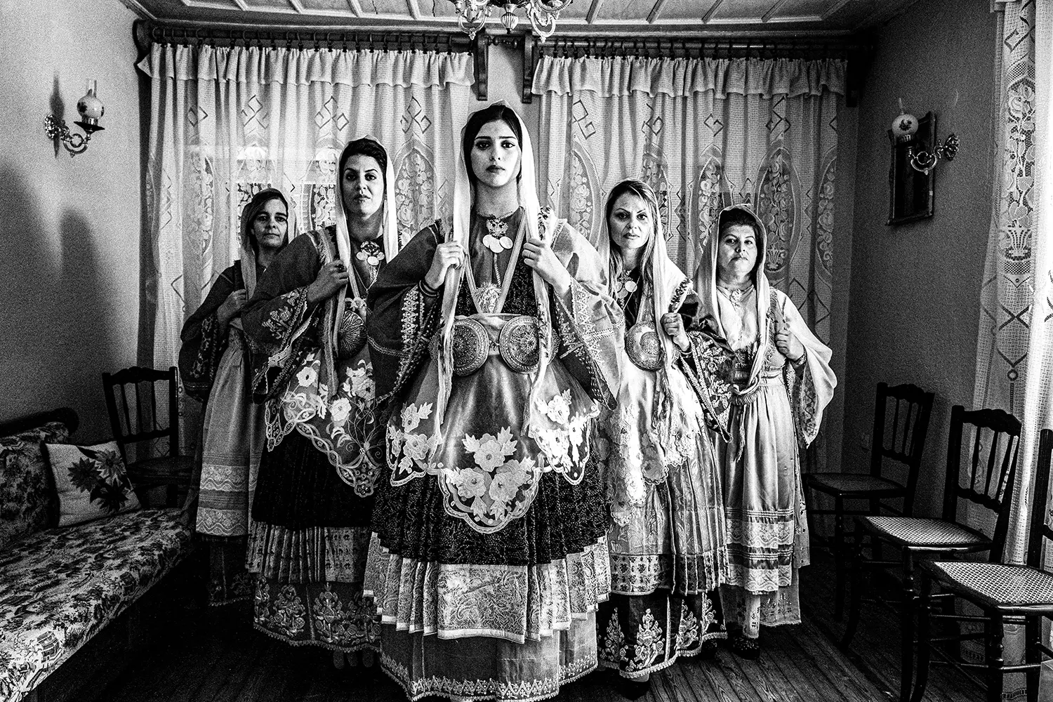 A group of women inside a traditional home, wearing the local costumes of Trikeri, Thessaly, Greece. Black and white photography by George Tatakis