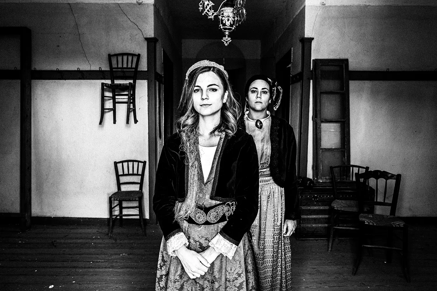 Two women inside a traditional home in Pinakates, wearing the local costumes of Pelion, Thessaly, Greece. Black and white photography by George Tatakis