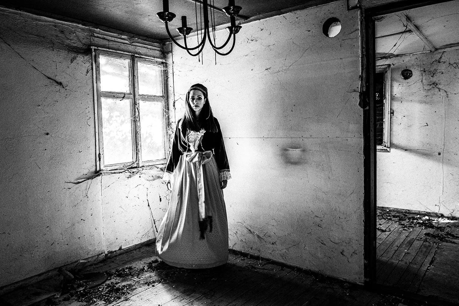 A woman inside a local abandoned house, wearing the traditional dress of Pelion, Thessaly, Greece. Black and white photography by George Tatakis