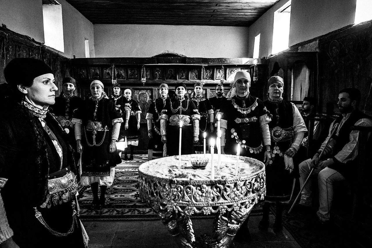 A group of 13 persons inside a local church at Prespes Lakes, Macedonia, Greece. Black and white photograph by George Tatakis