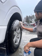 auto detailer scrubbing the tire of a vehicle 