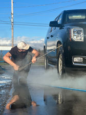 pressure washing the undercarriage of a black SUV
