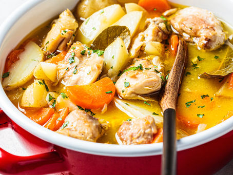Lemon garlic chicken stew with vegetables and fresh parsley in a Dutch oven.