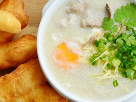 A bowl of congee with ginger, chicken, egg, scallion and cilantro.
