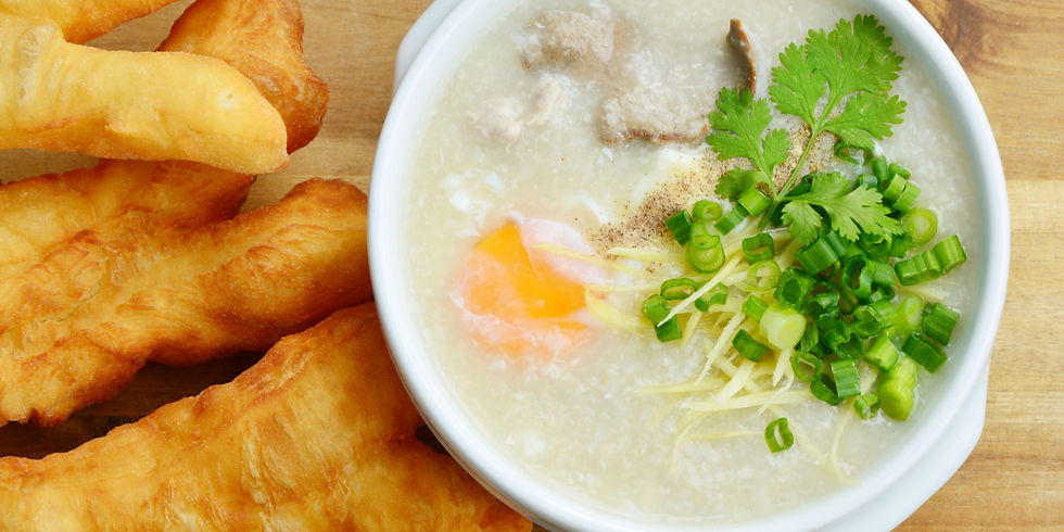A bowl of congee with ginger, chicken, egg, scallion and cilantro.